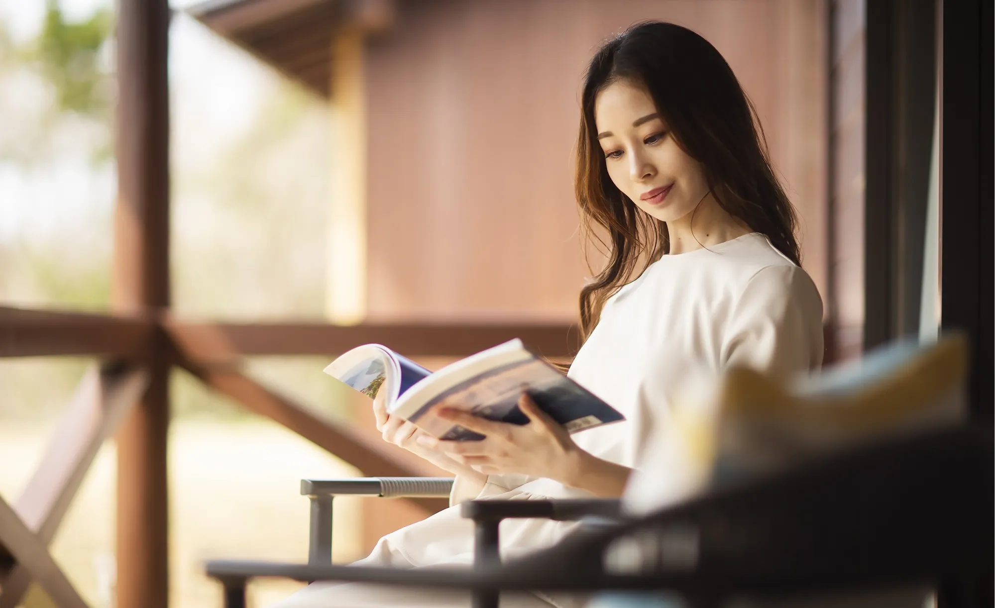 離れのテラスで読書する女性